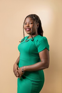 Headshot of a woman wearing a green shirt against a beige backdrop