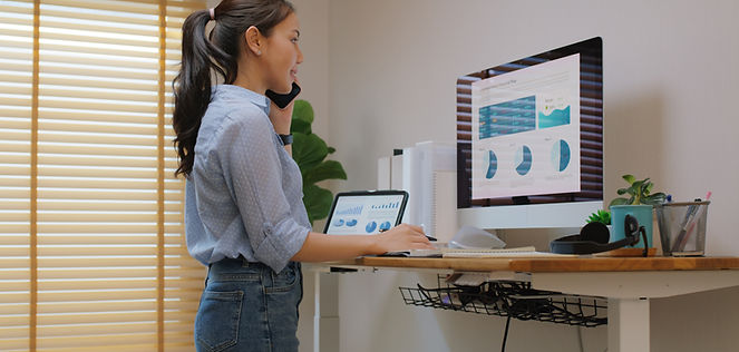 Electric adjustable standing desk in small office workspace for PC desktop computer worker