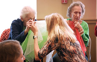 A mom and an elderly woman playing peek a boo with scarves