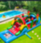 Colorful rainbow tropical bounce house and water slide combo with splash pool.