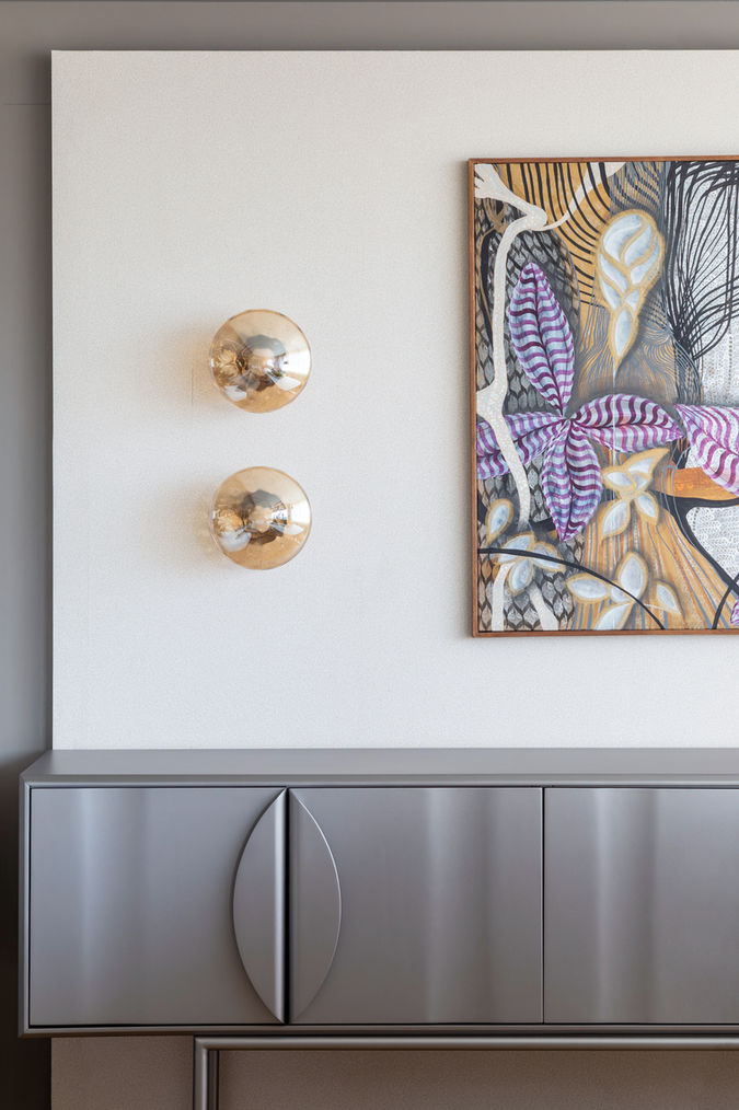Aparador com acabamento refinado, luminárias decorativas e obra de arte em destaque.