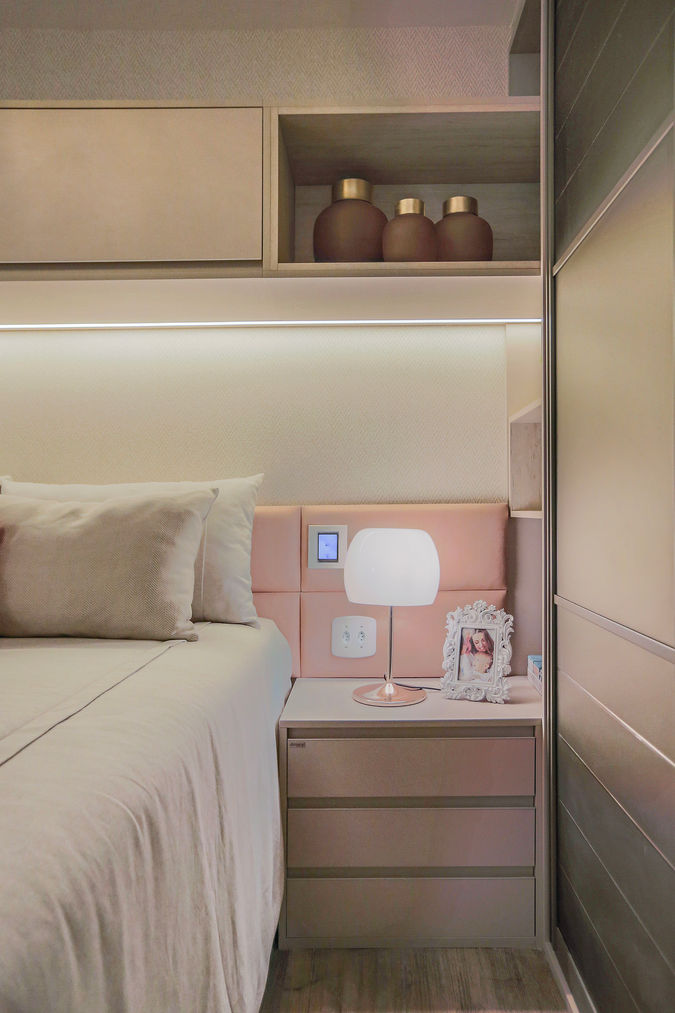 Suíte principal com cama queen, cabeceira estofada, marcenaria sob medida em tons neutros, iluminação indireta e detalhe em almofada vermelha. Design elegante e acolhedor em quarto de casal.