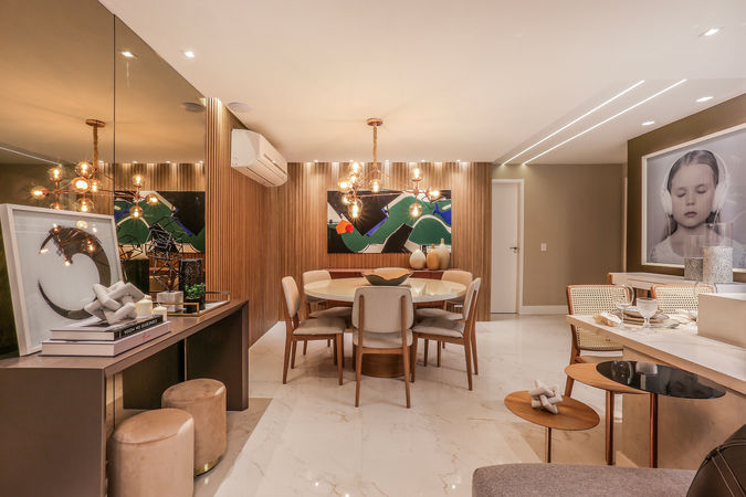 Sala de jantar sofisticada com parede ripada em madeira, mesa redonda laqueada, lustre escultural e obra de arte colorida. Projeto de interiores elegante e acolhedor em apartamento de alto padrão.