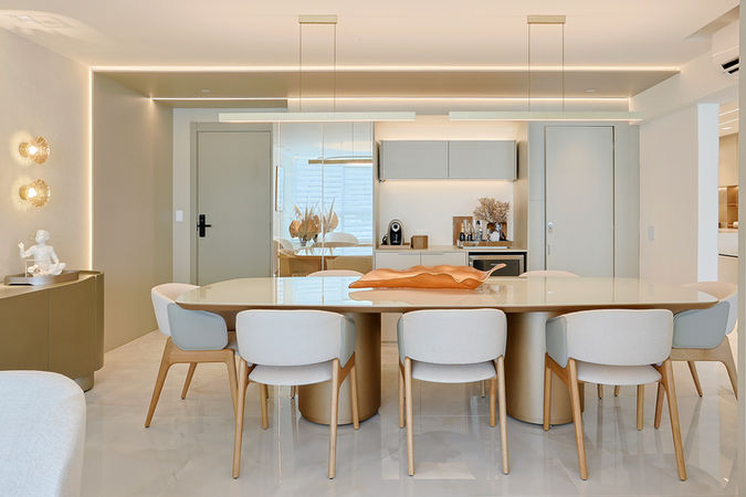 Sala de jantar integrada com cadeiras claras, conectada à sala em conceito aberto.