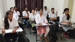 a group of people sitting at desks in a room.