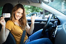 Glückliche junge Frau zeigt ihren neuen Führerschein im Auto