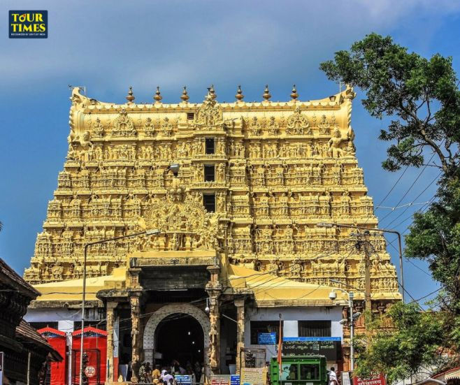 Golden temple facade with intricate carvings, bright blue sky, and trees. Sign reads "TOUR TIMES." Visitors are at the entrance.maha kumbha mela