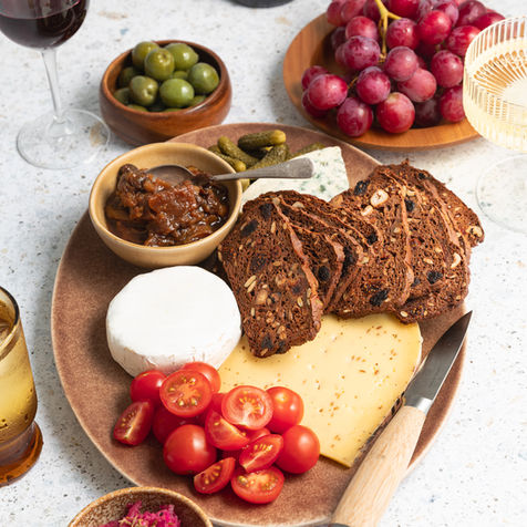 A platter of cheese and crackers surrounded by other food and wine glasses