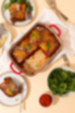 Eggplant parmigiana on a table with pieces taken out on it and placed onto plates