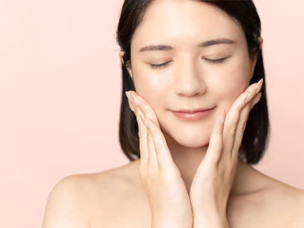 Woman touching her cheeks, representing pitted scar awareness and skincare