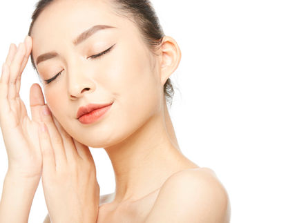 Woman gently touching her face with closed eyes, representing skincare awareness for atrophic scars