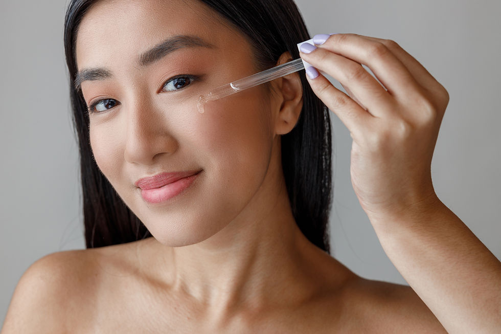 Asian woman gently applying serum for acne scars on her cheeks while smiling