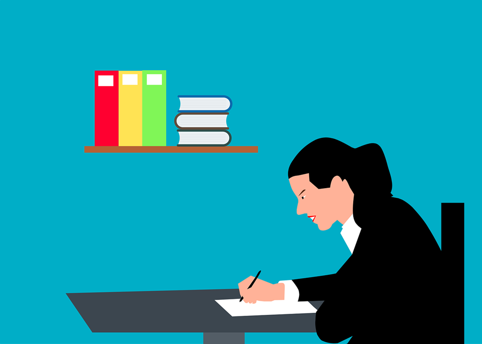 Woman writing at a desk in a journal, focused expression. Background: blue wall with a shelf holding colorful folders and stacked books.