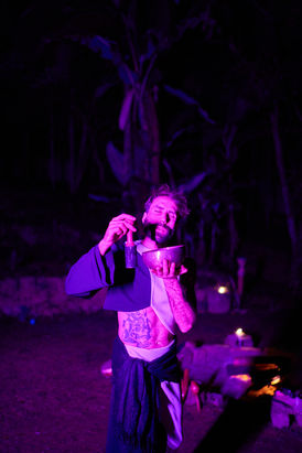 Homem tocando tambor xamânico sob luz verde em experiência de fotografia meditativa.