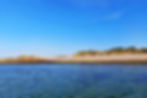 A sandy shoreline with a group of rocks on the left hand side