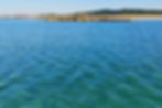 A low lying group of rocks in a calm blue sea