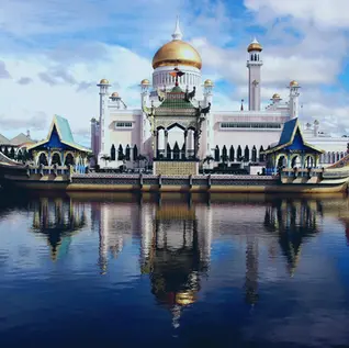 Ceremonial barge at Omar Ali Saifuddien Mosque with golden dome reflected on lagoon in daylight