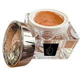Illuminator foundation in an open glass jar with peach-toned cream, designed to give mature skin a soft natural glow.