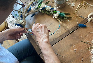 participante d'un atelier floral entrain de confectionner une couronne de fleurs séchées
