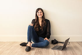 Woman sitting on the ground with camera and laptop next to her