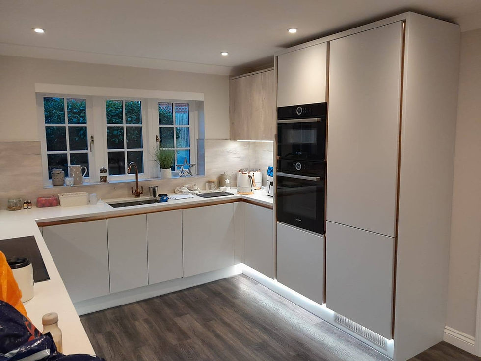 Modern kitchen with cream cabinetry, double oven, induction hob, and spotlighting beneath a sleek extractor hood.