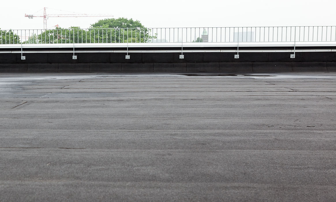 a flat roof with roofing and fencing