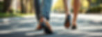A man and woman walking along a sunny sidewalk.