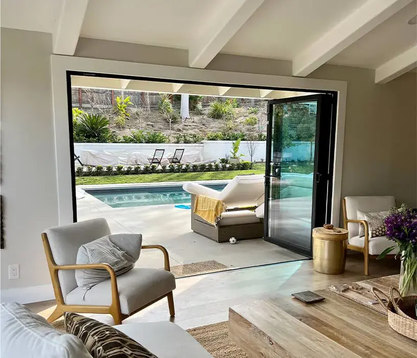 Modern interior design featuring large black-framed folding glass doors and expansive windows by EZ FOLD A DOOR, showcasing a seamless indoor-outdoor living concept in a luxury property.