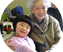Senior and child looking at the camera, sitting in an embrace and smiling.