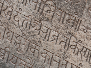 Mantras in Sanskrit auf einer Steinwand