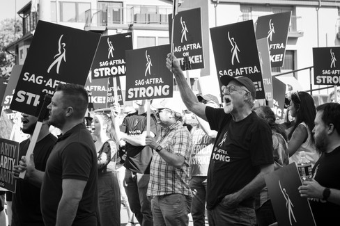 A grayscale photo of protesters holding signs and shouting mid-chant.