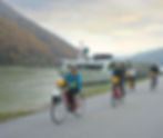 Travellers enjoy a bicycle ride along the shore while their Tauck rivercruise boat follows