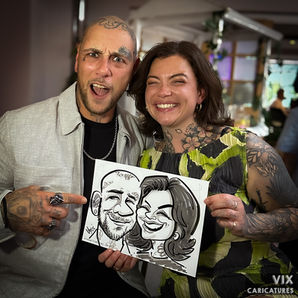 Couple with tattoos holding their caricature with funky pose. Caricature drawn by Vix Caricatures at a wedding.