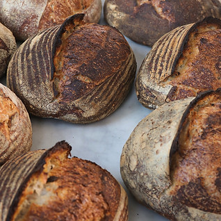 A photo showing a composition of crusty bread loafs with flour sprinkled on top