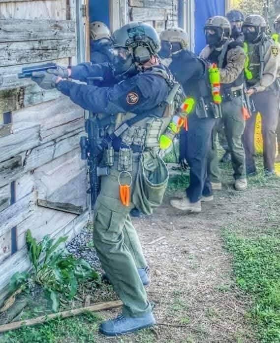 Professionals in protective equipment practicing a training scenario at Camp Liberty