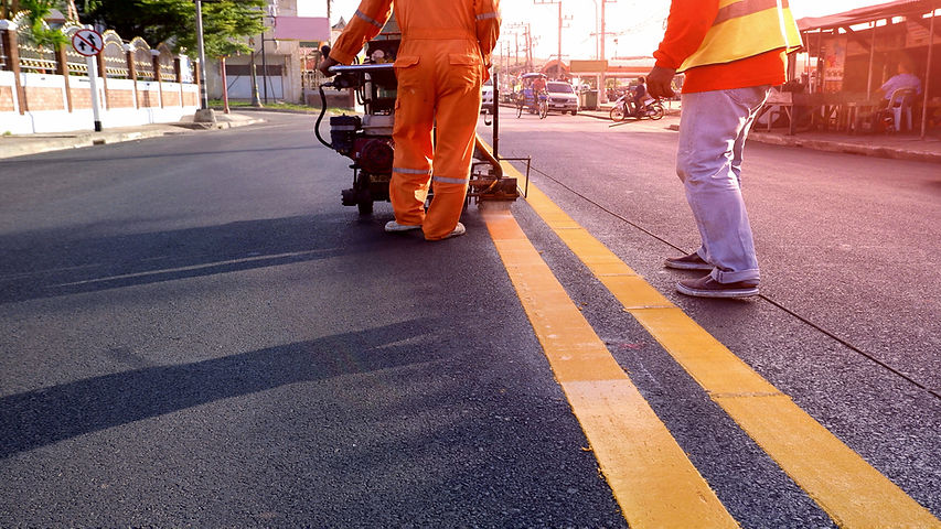 Rear view of 2 Road workers with thermoplastic spray marking machine working to Paint yell