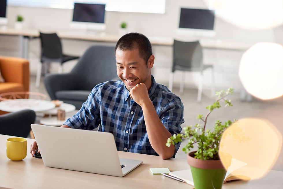 Young Asian designer smiling confidently while sitting alone at a desk in a modern office