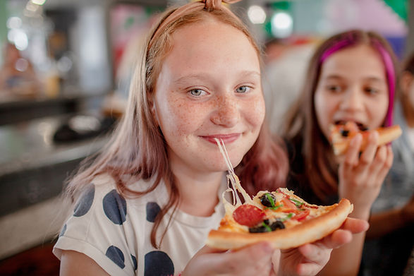 Happy children eating pizza with appetite in pizzeria. People together have fun, enjoy tim