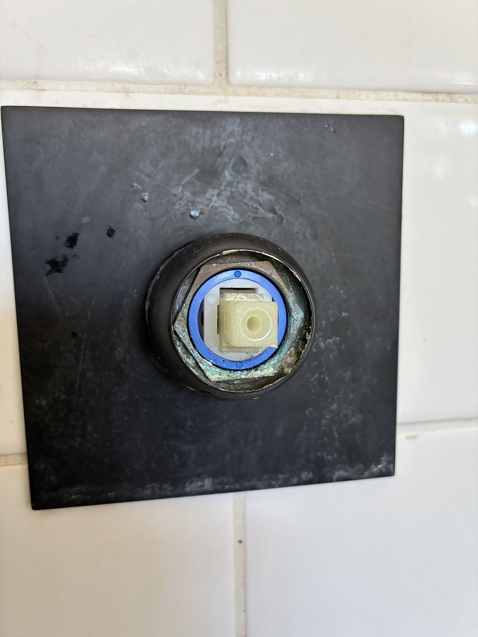 Exposed ceramic cartridge inside a wall-mounted tap showing corrosion around the fitting.