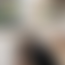 A licensed gas fitter in a black polo shirt with sky blue trim connecting copper gas pipework under a kitchen island, with a new stainless steel five-burner gas cooktop installed in the white stone benchtop above, in a modern Brisbane home.