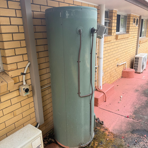Leaking hot water system with water pooling at base indicating tank failure