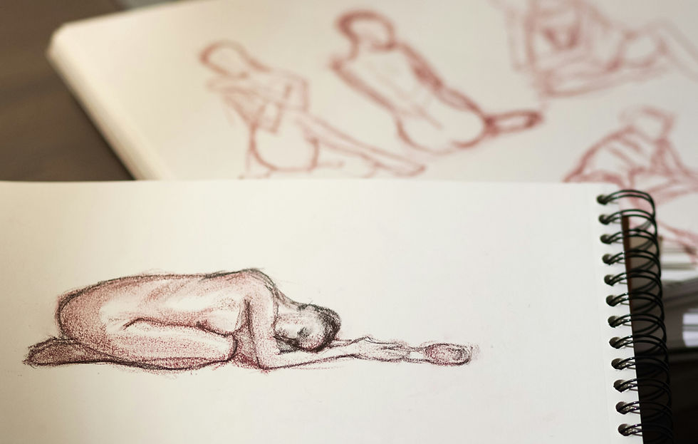 A spiral-bound sketchbook open to a drawing of a figure in a child’s pose, symbolizing vulnerability and embodied connection. In the background, additional gestural figure drawings are visible.