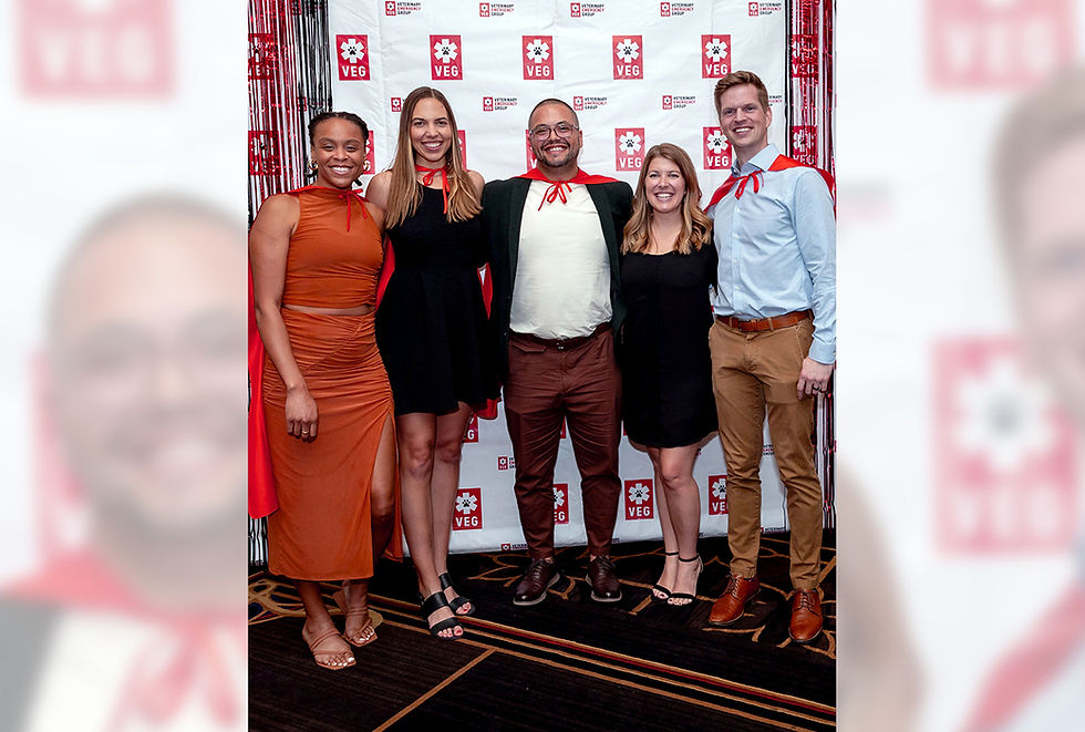 Five smiling VEG employees stand against a backdrop of the company's logo