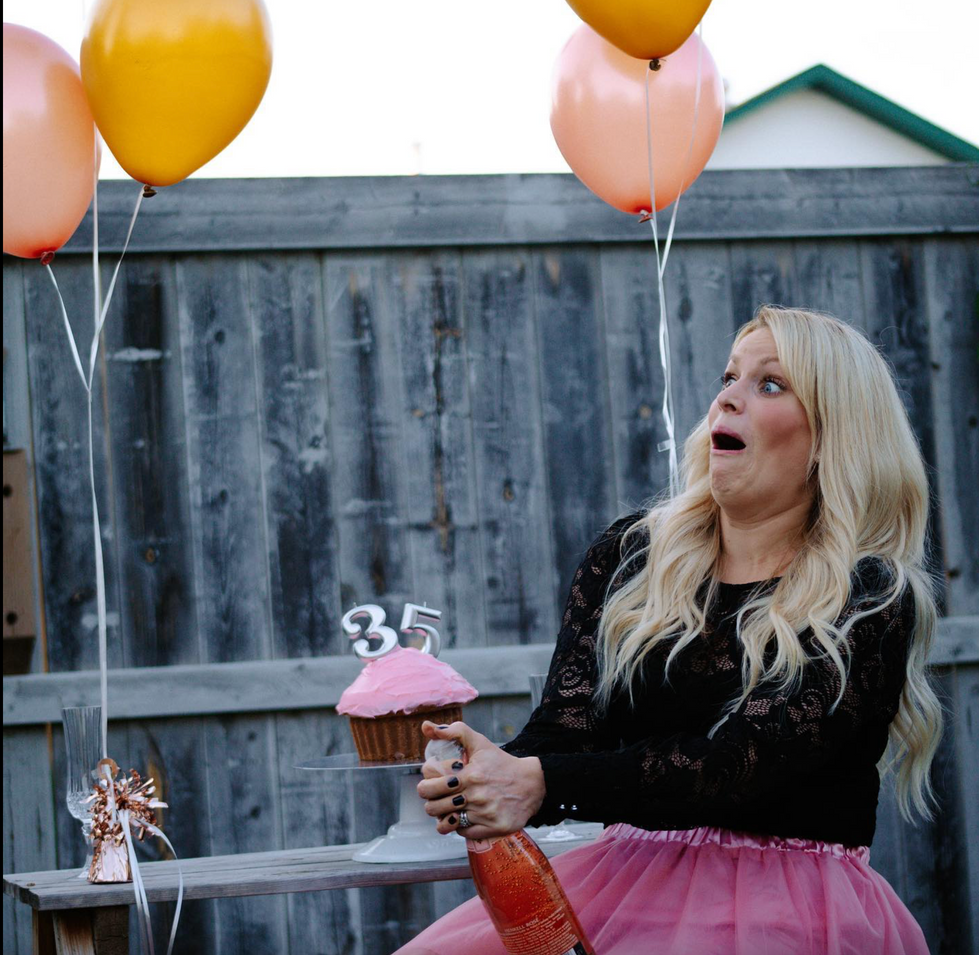 a woman holds a bottle of champagne in front of a cupcake with the number 35 on it