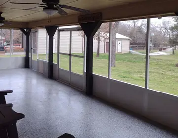 Spacious screened porch with gray flooring, offering backyard views