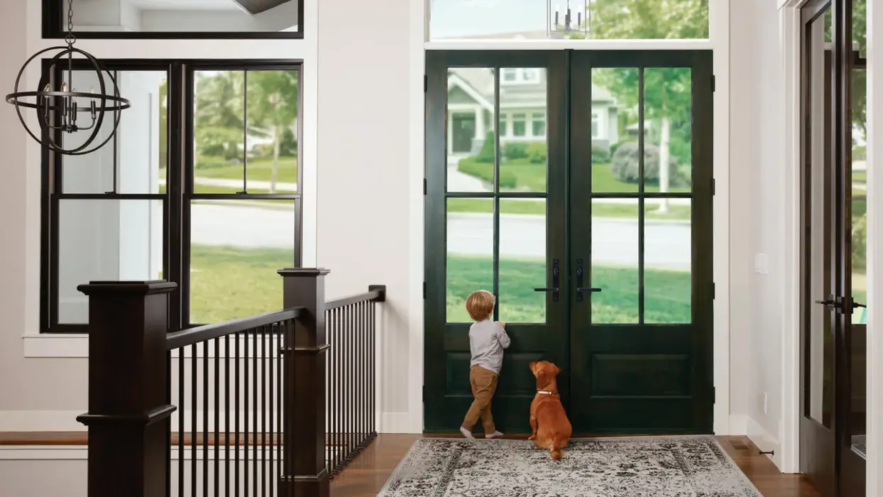 Child and dog by HomeStop's black French doors