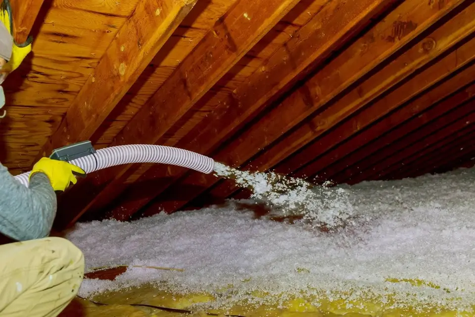 Worker installing blown-in attic insulation