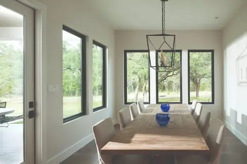 Modern dining room with large black-framed windows, wooden table and chairs