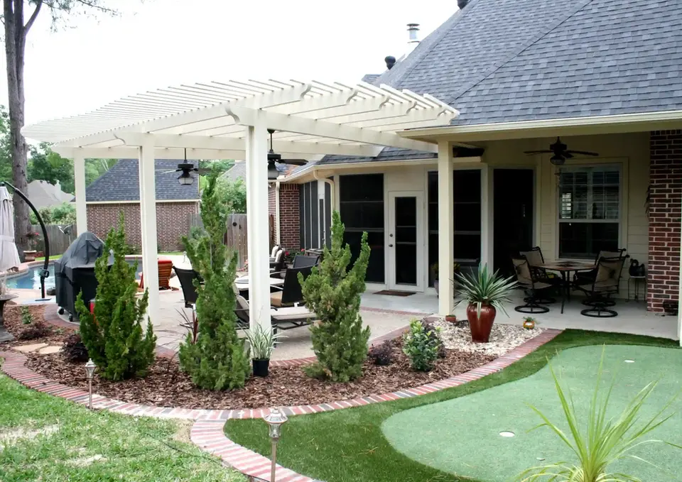 White pergola shaded patio with potted plants and putting green