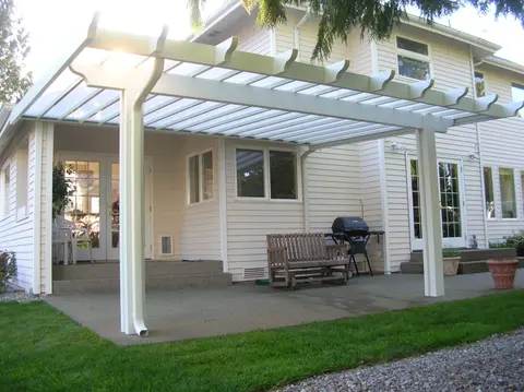 White pergola covering patio with bench and grill